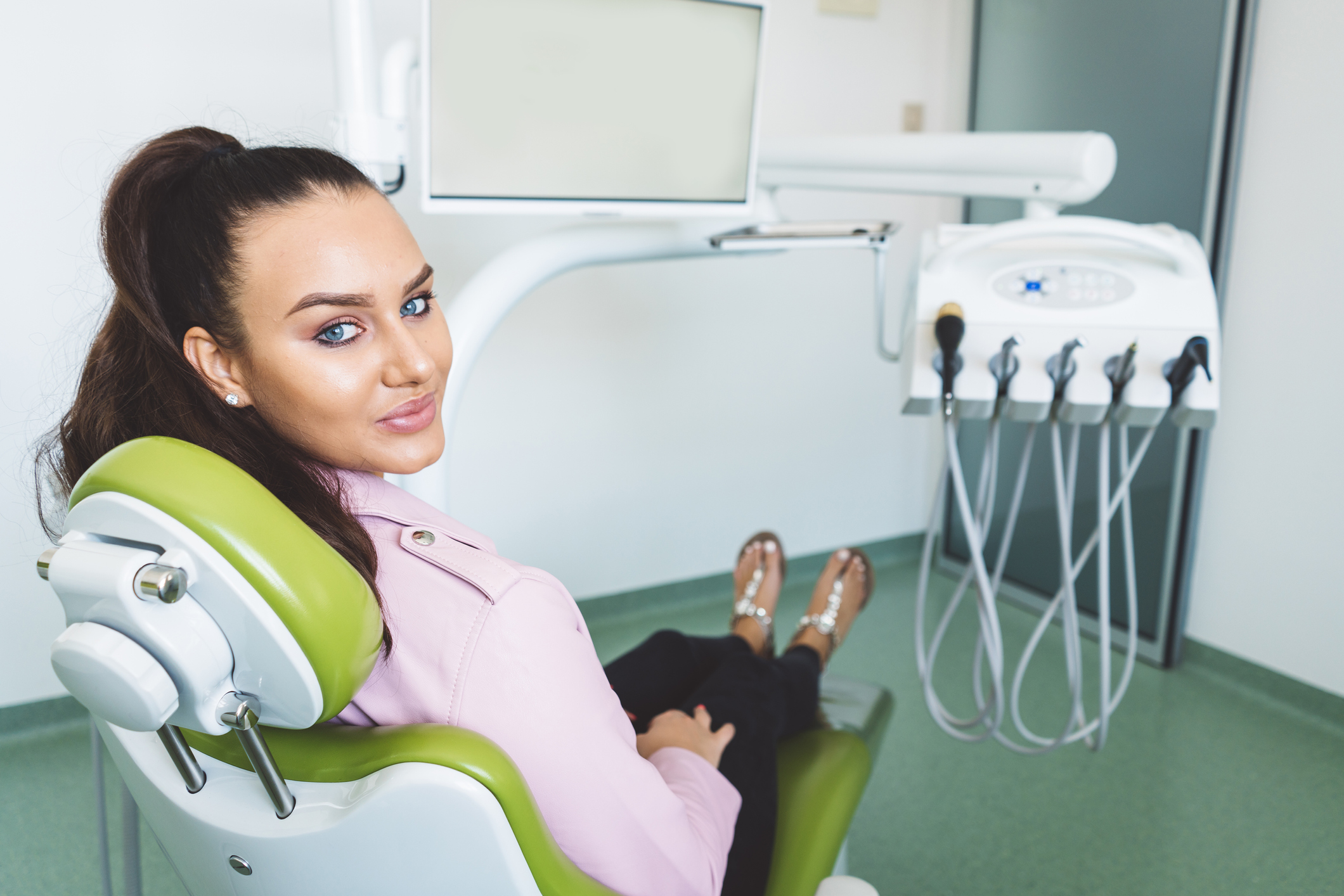 happy woman sitting in a green chair at the oral surgeons office